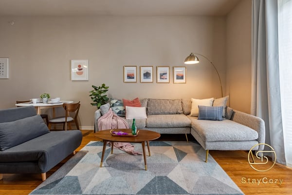 Modern living room with gray sectional sofa, dark blue armchair, wooden coffee table, and arc floor lamp